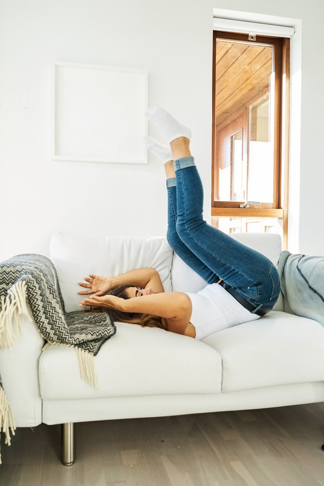 Woman relaxing with legs up on a white couch