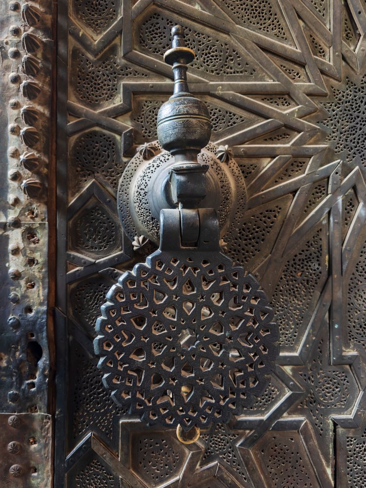 Ornate metal door knocker with intricate geometric patterns on a historic metal door at Medresa El Bouanania, Landscape, Lifestyle, Fes, Fecs-Meknes Administrative Depar, Morocco.