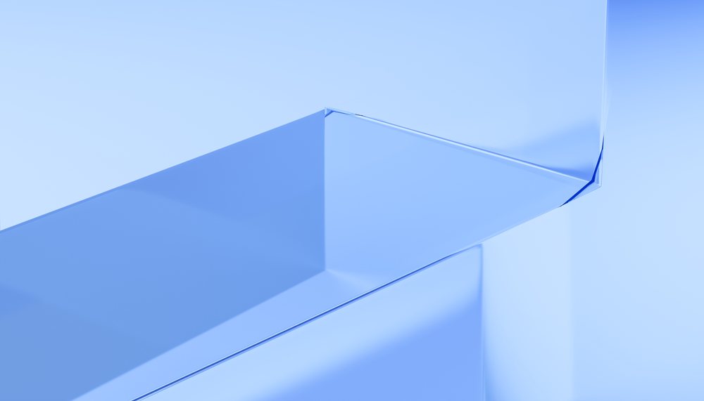 Abstract blue geometric shapes with smooth glass-like surfaces and reflections in a minimalist digital render studio.