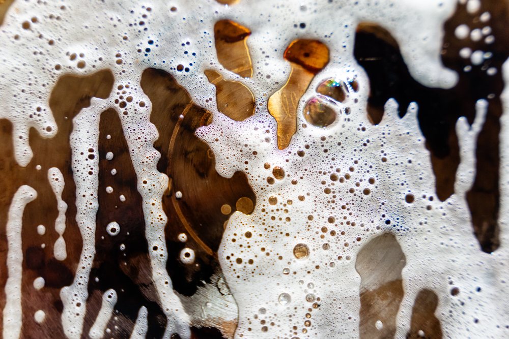 Close-up showing foam and carbonation bubbles on the surface of a brown liquid drink with detailed texture, abstract texture, background, wallpaper, Spain.