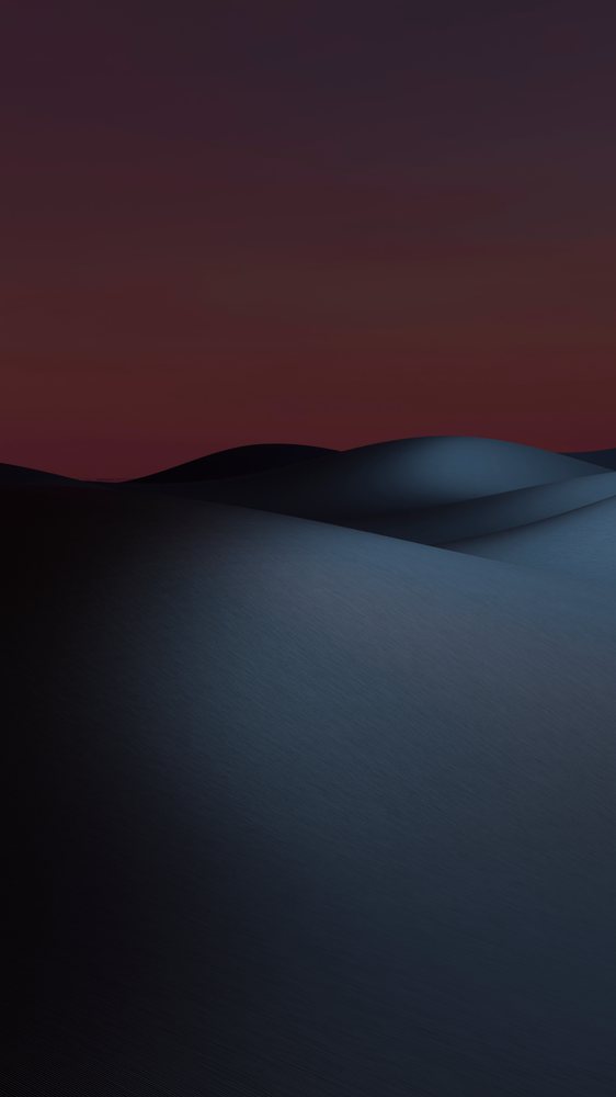 Moonlit sand dunes with ripple patterns under a dark nighttime sky.