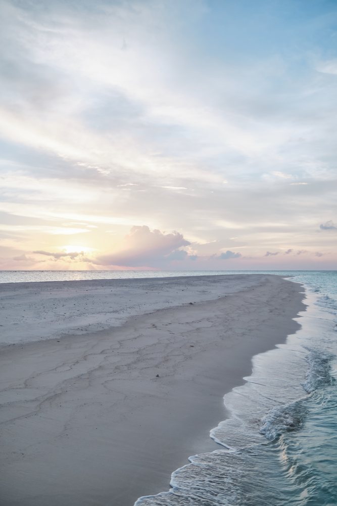 A tranquil beach shoreline at sunset in the Maldives