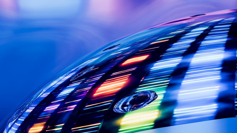 Colorful light streaks reflecting on a curved glass surface with water droplets on a blue background.