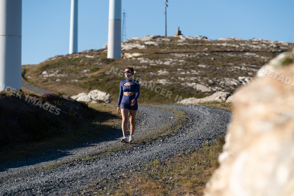 A white woman walks outdoors on a rocky trail