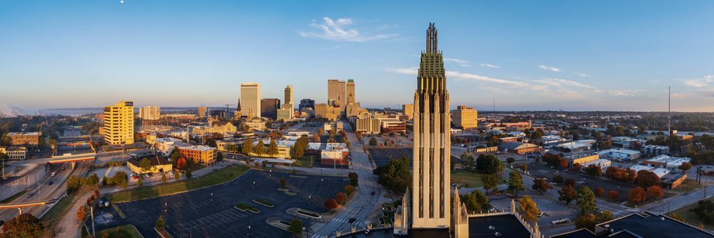 Tulsa skyline at Sunrise featuring downtown buildings and a prominent tall tower under clear sky with autumn trees, Americana, Historic, Oklahoma, USA.