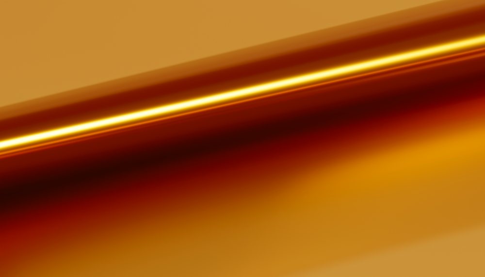 Abstract smooth and shiny golden liquid texture with warm gradient tones.