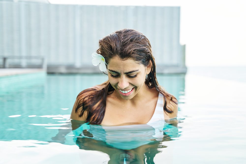 A white woman smiles while standing in an outdoor swimming pool
