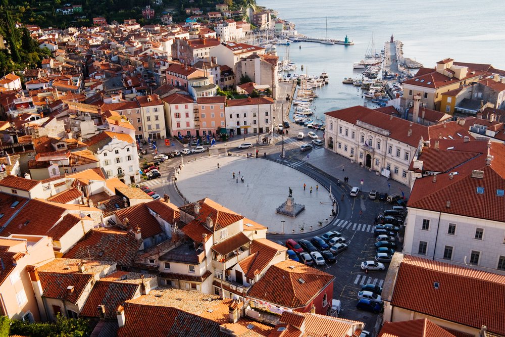 Tartini Square with a central statue and marina filled with boats in coastal, Piran, Slovenia.