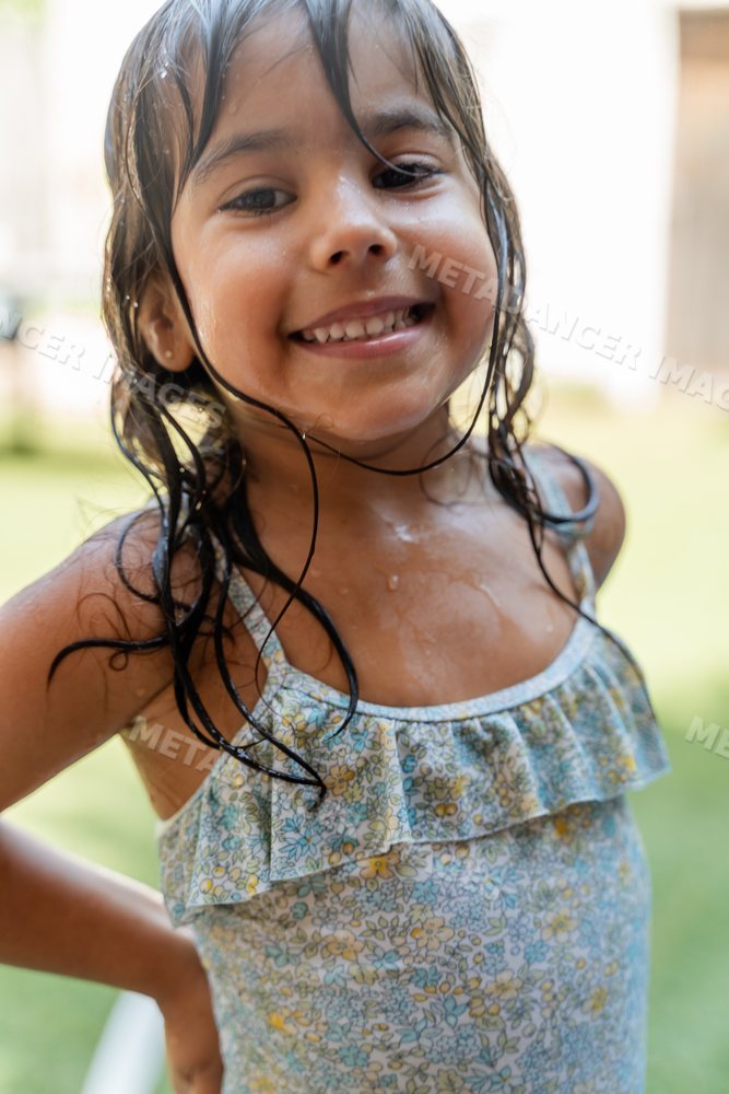 Smiling young white girl enjoying outdoor water play in summer