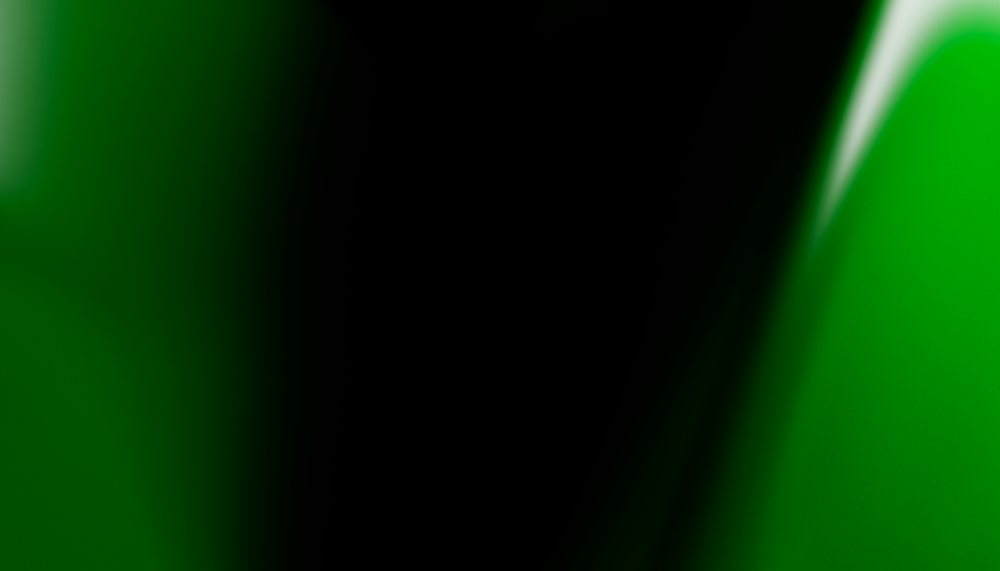 Abstract green and black gradient background featuring smooth color transitions with glowing effects.