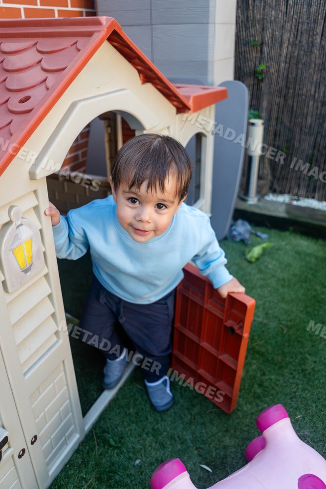 A toddler white boy steps out of a plastic play structure