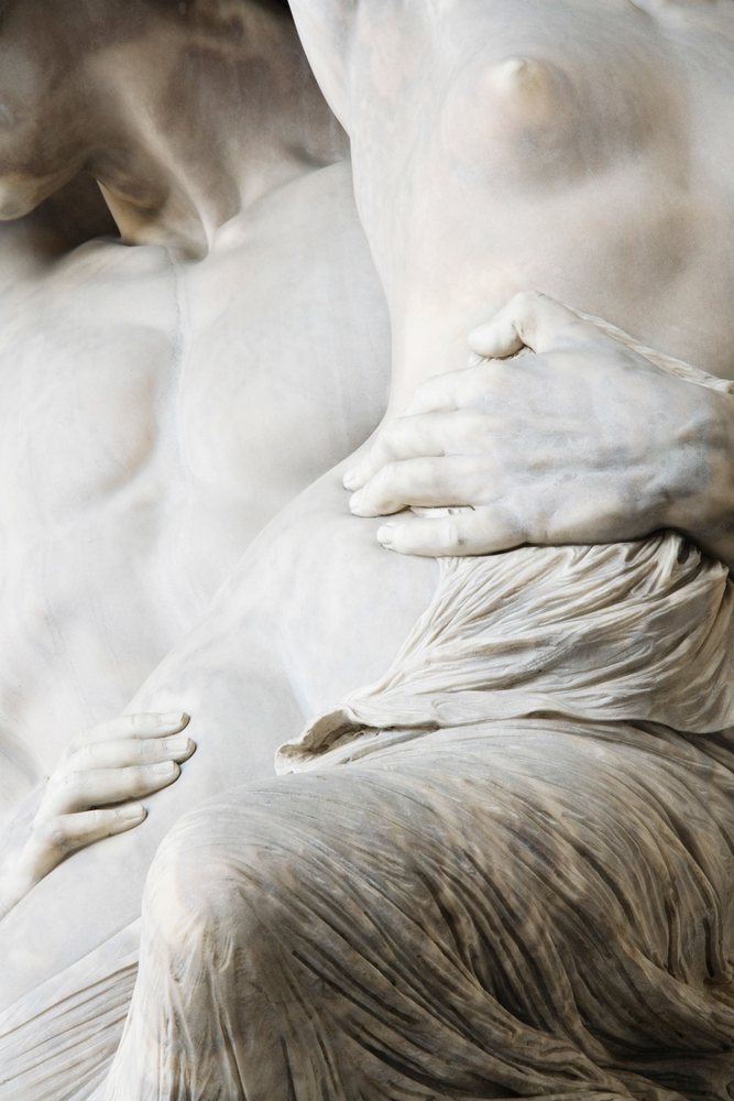 Detail of a marble sculpture showing intertwined male and female figures with carved drapery, Florence, Italy.