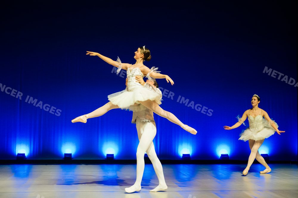 Ballet dancers perform a lift on stage during a holiday-themed dance