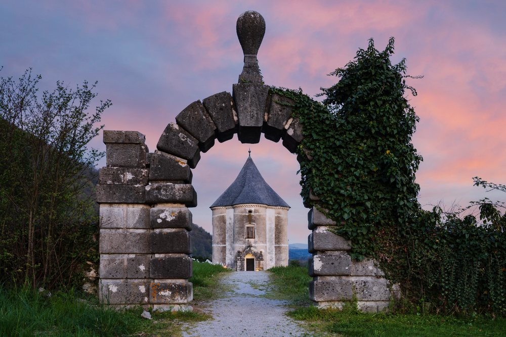 Historic Hudičev Turn tower framed by a stone arch covered with ivy at dusk, landscape, cityscape, Soteska, near Dolenjske Toplice, Slovenia.