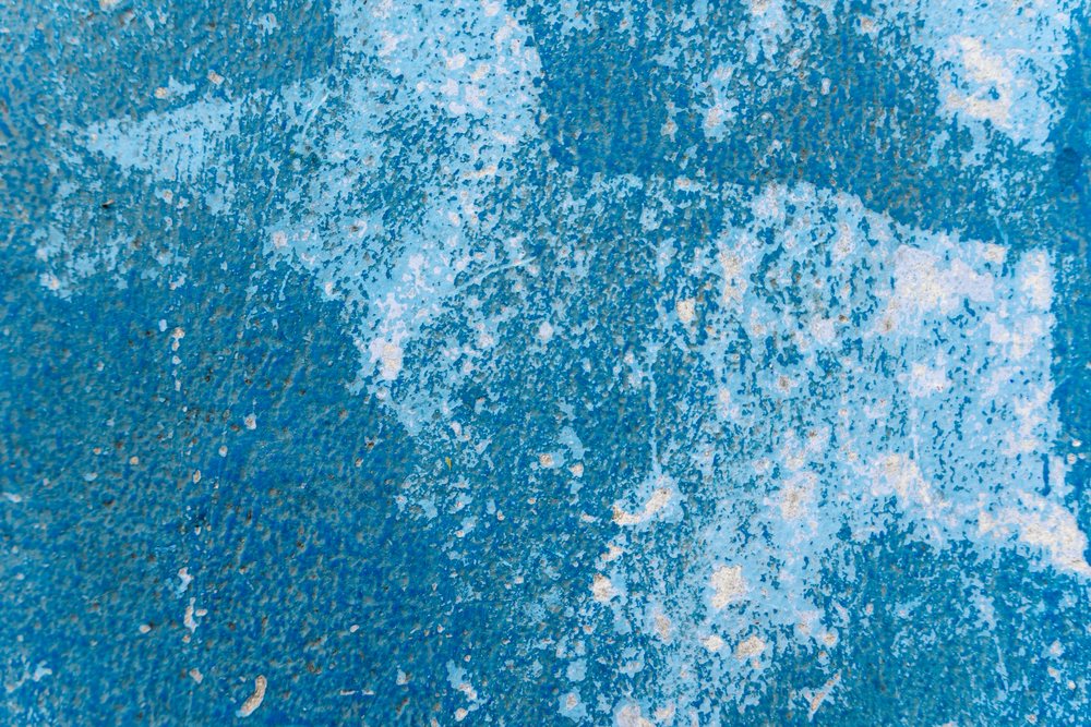 Blue textured surface with peeling, weathered, and scratched paint showing surface imperfections, texture, abstract texture, background, wallpaper, Spain.