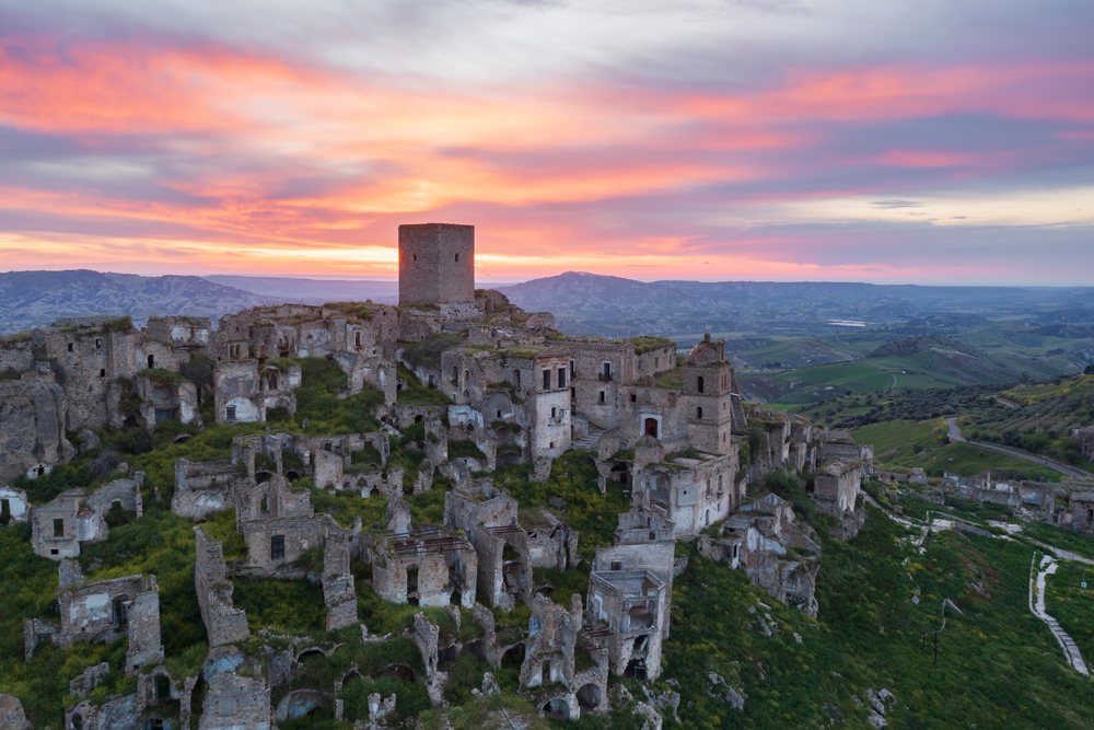Ruined city of Craco with ancient stone buildings on a hillside at Sunrise, Basilicata, Italy.