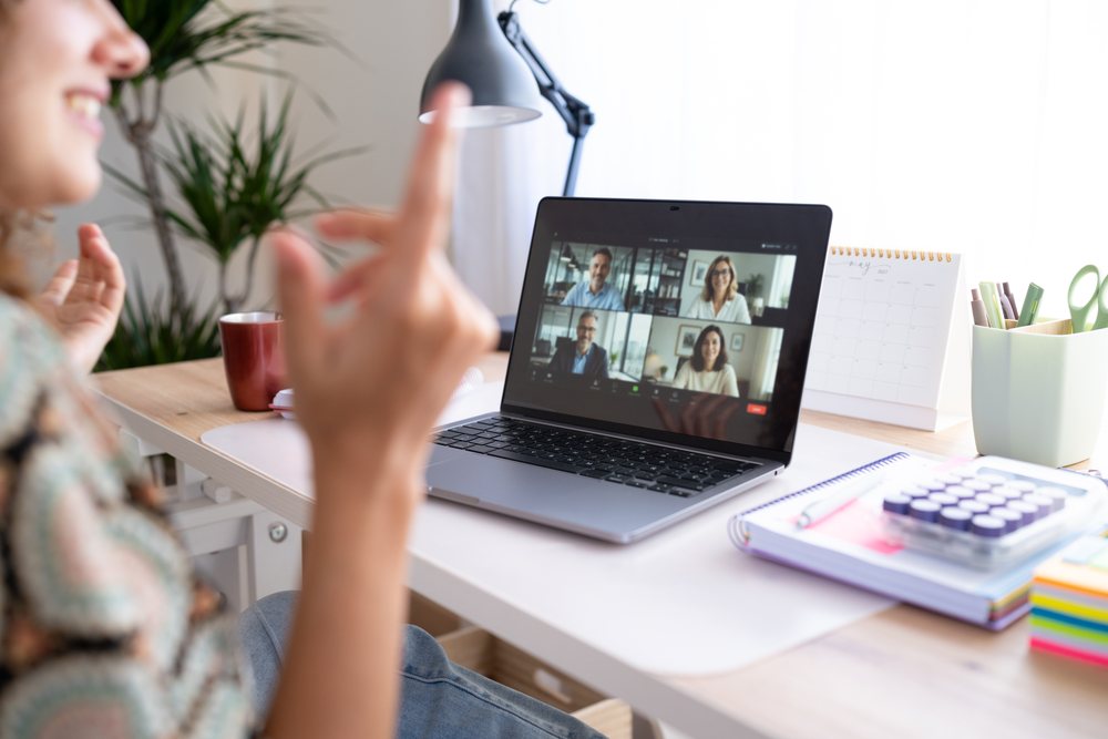 Woman sitting at a desk using a laptop for a video call in a home office setting, Spain.