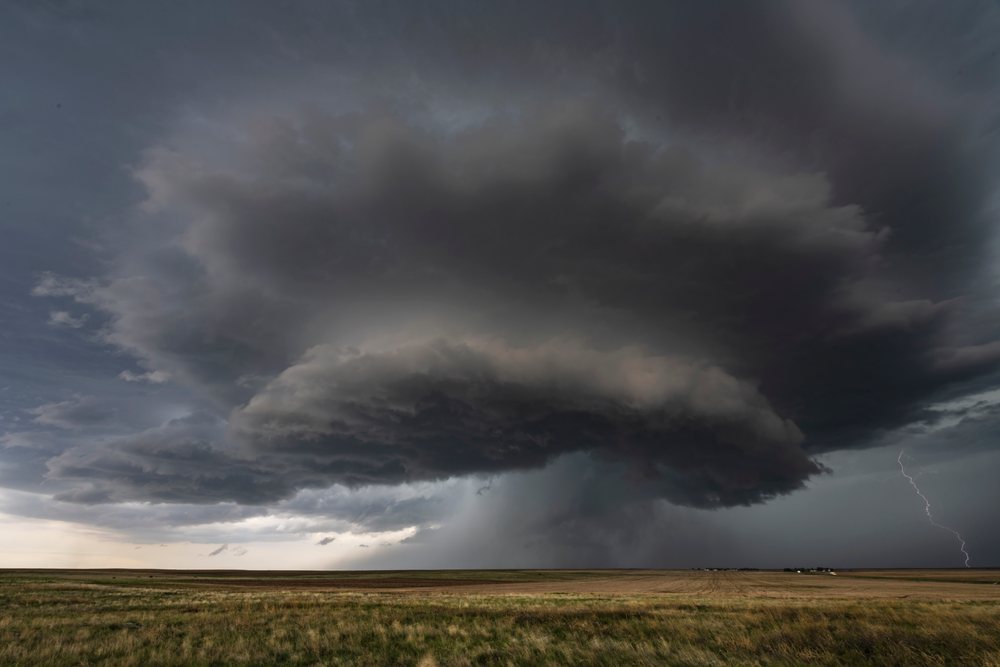 Supercell storm with dark thunderstorm clouds and lightning strike over open grassland in Tornado Alley, Merino, Colorado, USA.