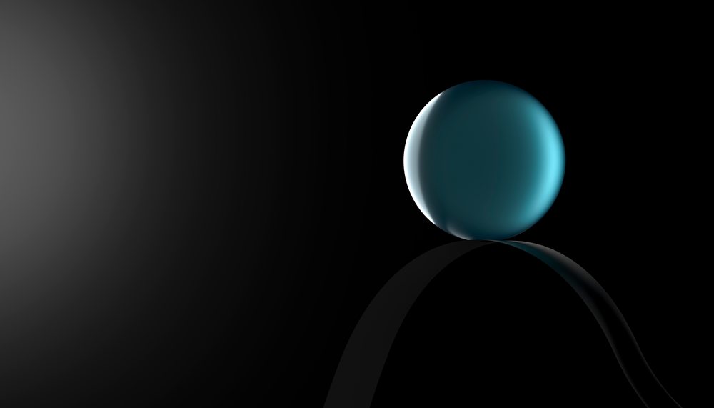 A glossy blue sphere is balanced on a curved reflective surface against a dark background.