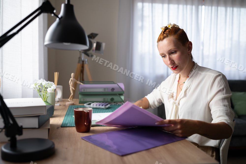 White Woman working with paperwork at a home office desk in Galicia