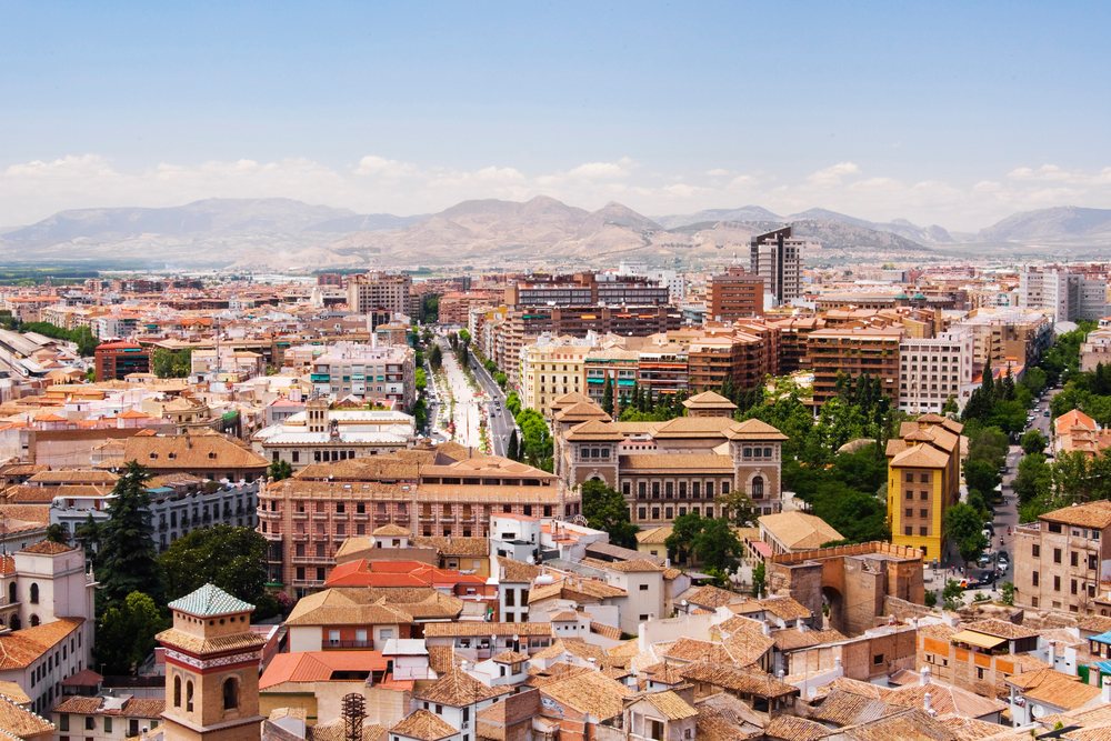 Urban cityscape of Andalucia, Spain showing buildings and rooftops with mountains and a clear blue sky during daytime.