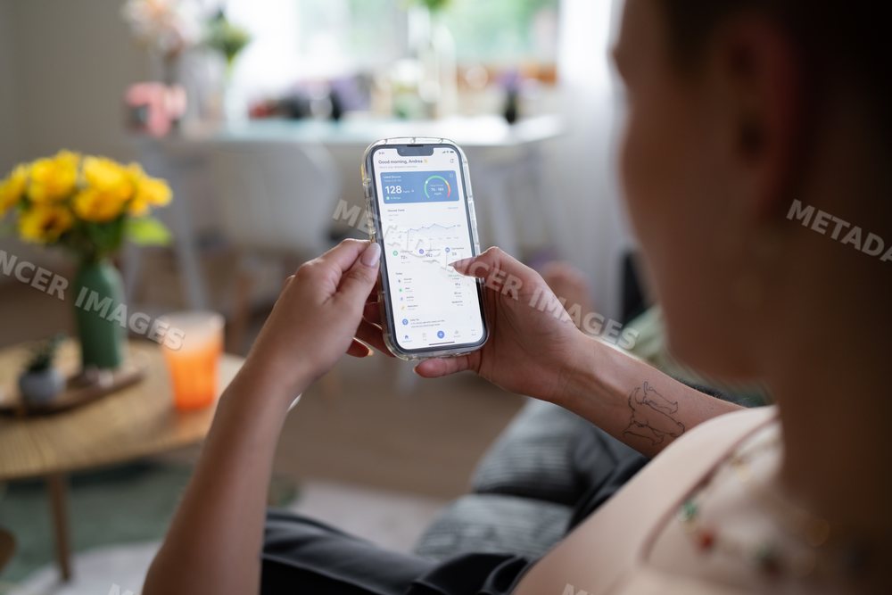 A white woman checks her glucose levels on a health app while at home