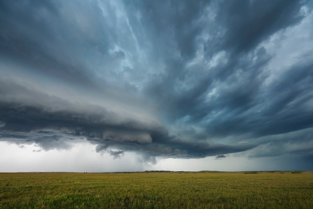 Storm clouds gather over grassy plains near Butte Creek, indicating severe weather conditions, Storm Chasing, Environmental, Wood - Butte Creek, South Dakota, USA.