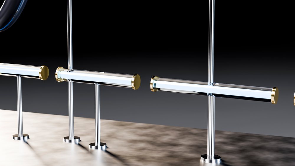 Metal railing with polished stainless steel horizontal handrails and vertical posts accented by gold caps in a modern industrial interior.