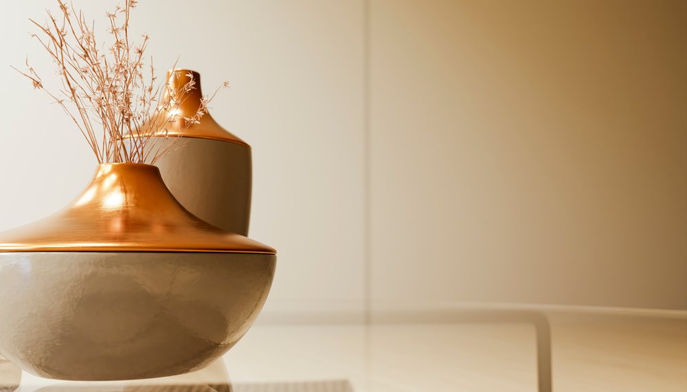 Two ceramic vases with dried flowers on a light-colored glossy table in a minimalist indoor setting.