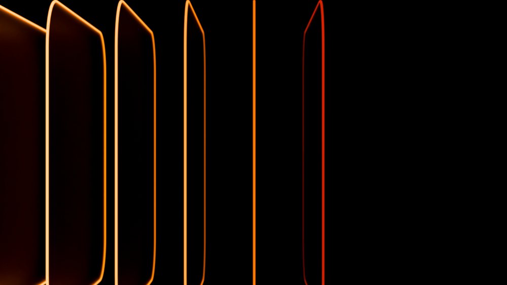 Vertical panels with glowing orange neon edges stand parallel against a dark background, creating a modern abstract lighting effect.