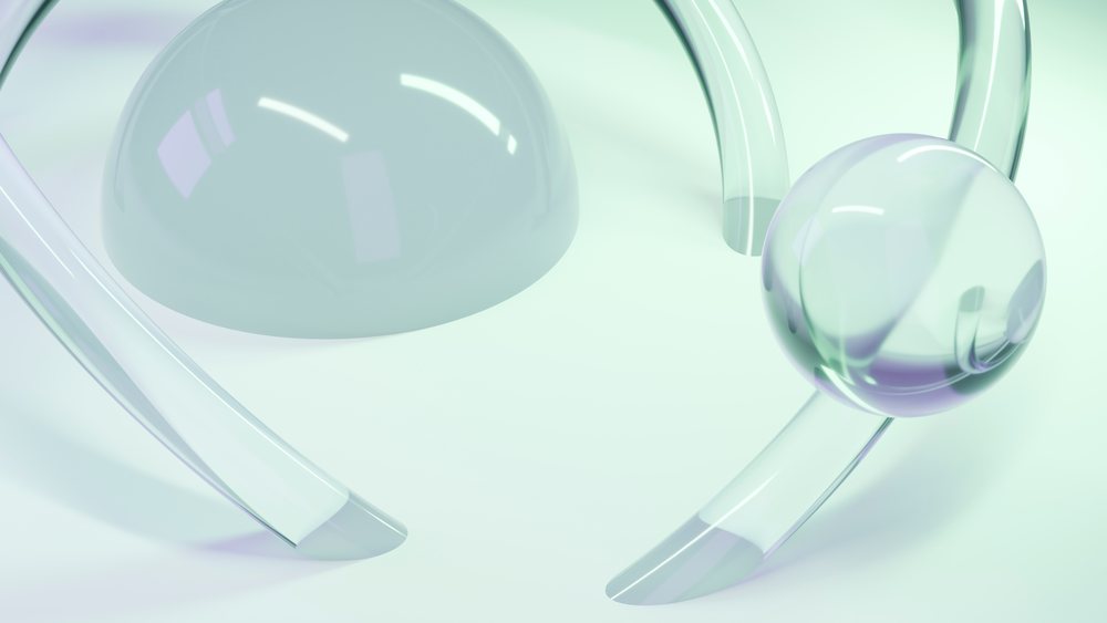 Large and smaller translucent glass spheres and curved tubes rest on a flat surface under soft greenish light.