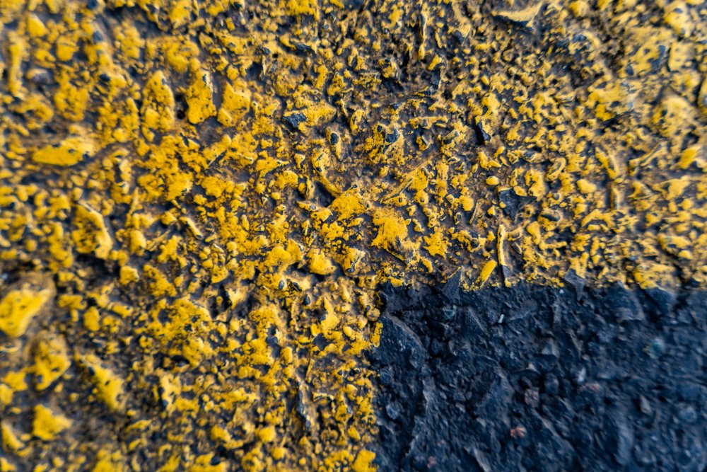 Close-up of a rough asphalt surface with weathered yellow and black road markings outdoors, texture, abstract texture, background, wallpaper, Spain.