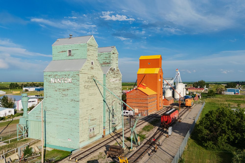 Grain Elevators and railway tracks alongside railroad cars in a rural agricultural industrial area, Canada under a clear sky, Storm Chasing, Weather, Environment, Nanton, Alberta.