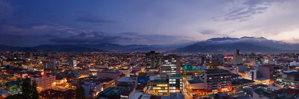 Cityscape of San Jose with illuminated buildings and mountains at dusk, Costa Rica.