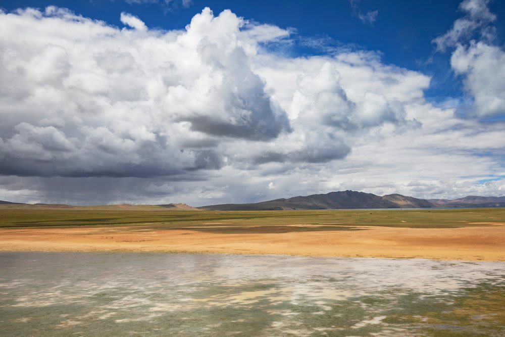 View of grassland and mountain range from the Roof of the World Train, under cloudy sky, Amdo County, Autonomous Region of Tibet.