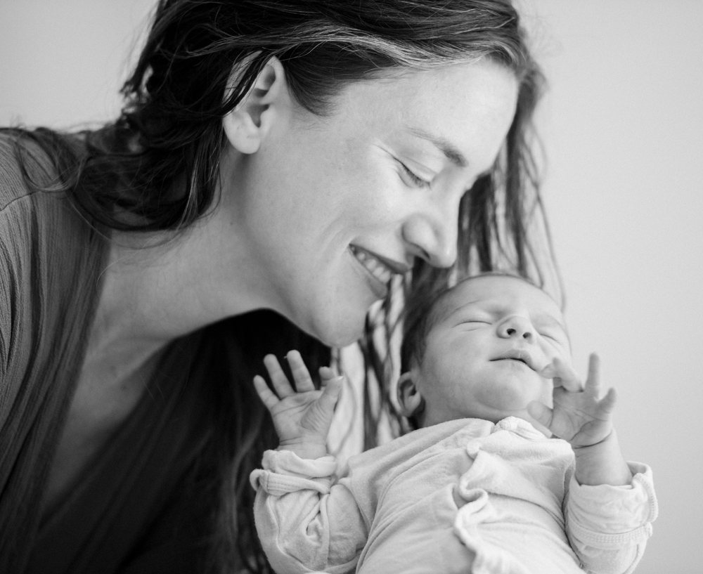 Mother smiles tenderly while holding her newborn baby close in a loving bonding moment, USA.