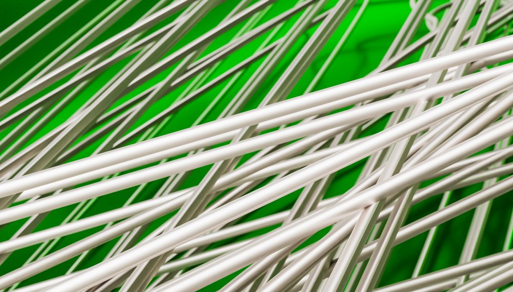 Uncooked white rice noodles rest in a green bowl.