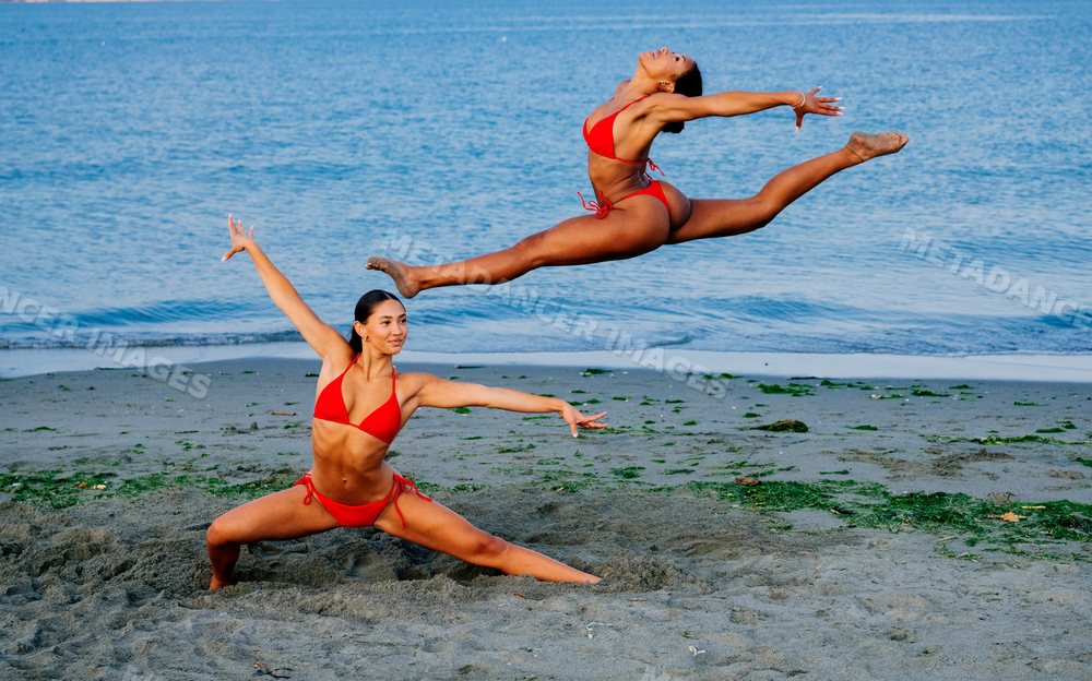 Two women performing partner yoga acrobatics on a beach in wa USA