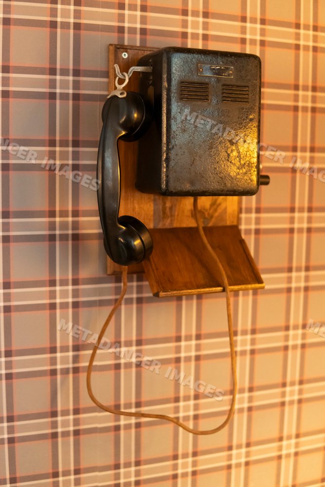 Retro black wall telephone with corded handset mounted on wood