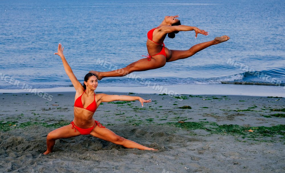 Two women perform partner acrobatics Yoga on a beach in WA, USA