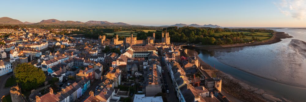 Aerial view of Caernarfon town and historic castle at Sunset beside river and coastal shoreline, Landscape, Gwynedd, Wales.