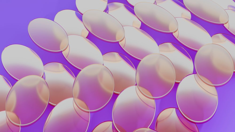 Multiple transparent oval gel capsules arranged closely on a purple background with smooth glossy surfaces and light reflections.