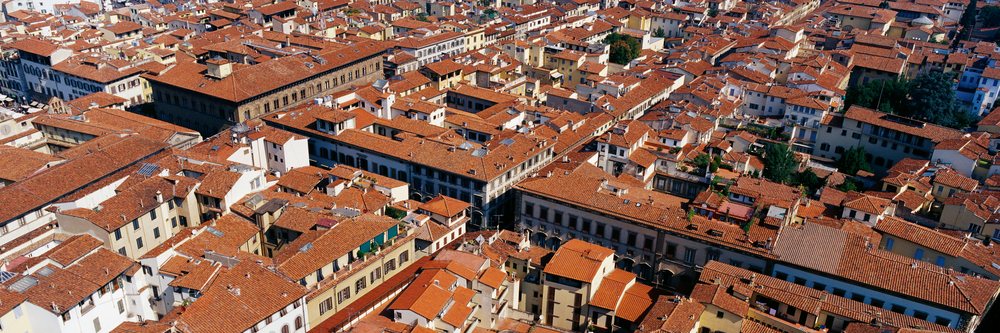 Aerial view of densely packed residential buildings with red tile roofs during the day, Cityscape Florence, Italy.