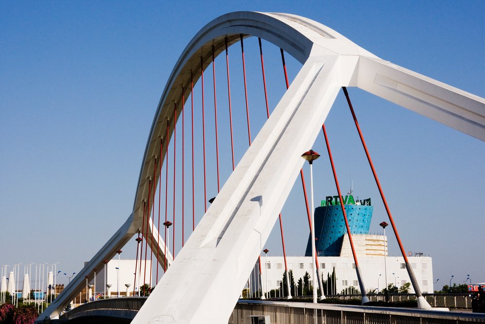 Puente del Cachorro bridge with white arch and red cables crossing a river, Spain under clear blue sky, Andalusia.