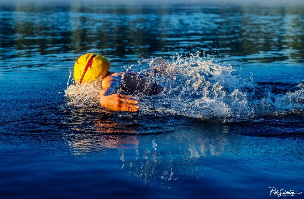 Swimmer wearing a yellow swim cap performing a freestyle stroke in open water, USA.
