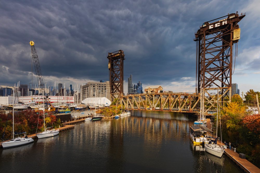 Canal Street Lift Bridge spans a river with boats docked at the marina and an urban Chicago skyline under a cloudy autumn sky, Americana, Historic, Illinois, USA.