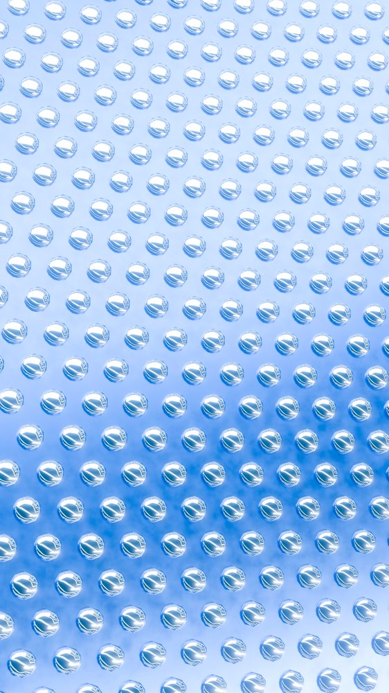 Close-up macro view of water droplets forming a pattern on a smooth reflective blue glass surface.