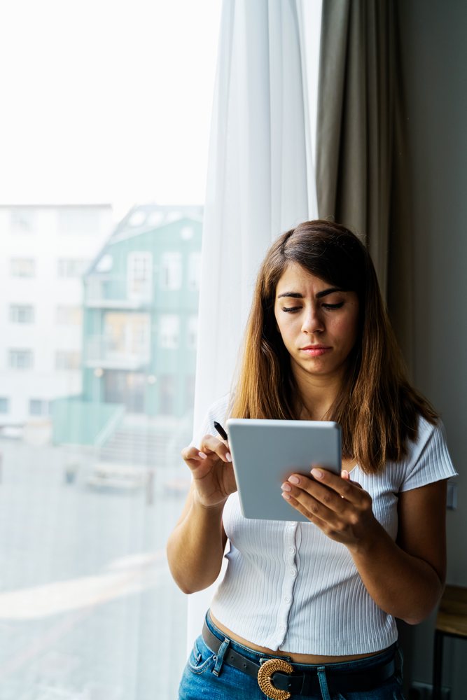 A woman uses a tablet indoors near a window in Iceland