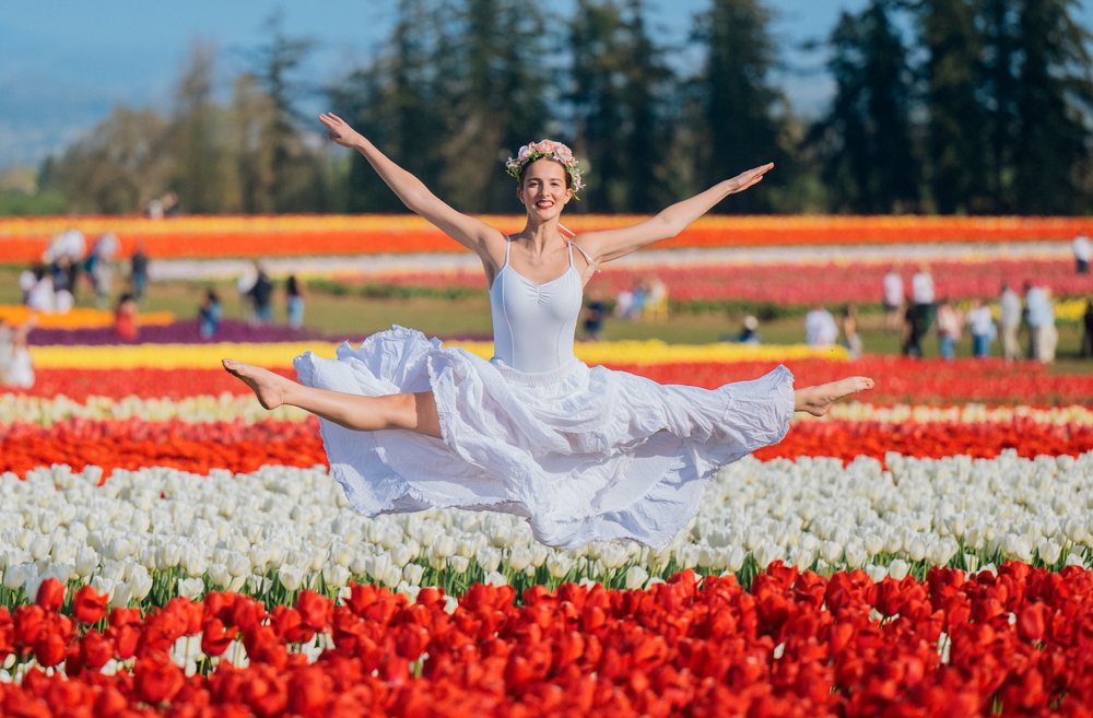 Ballet dancer leaps gracefully in a flowering tulip field outdoors in the USA during spring.