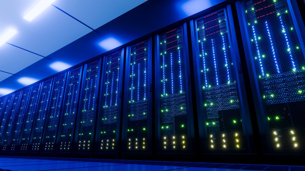 Modern data center server racks with multiple illuminated computer servers under blue lighting in a high-tech facility.